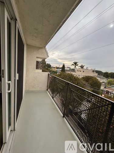 A balcony with a black railing and a view of buildings and trees.