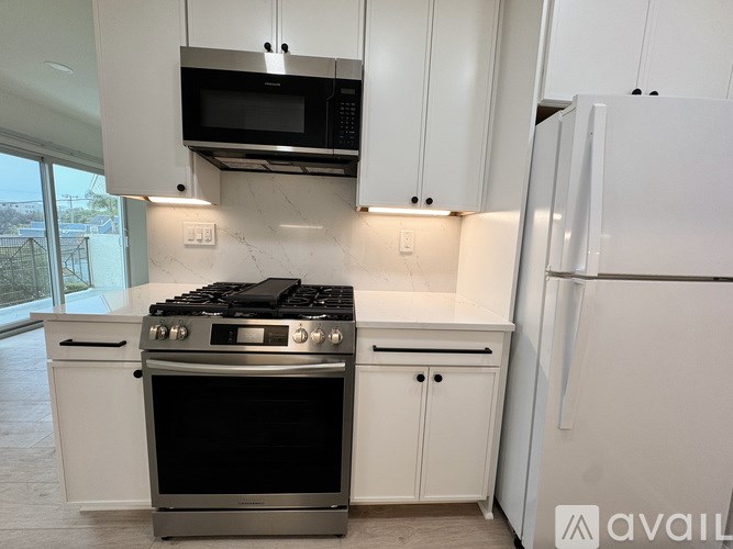 A modern kitchen with white cabinets and stainless steel appliances.