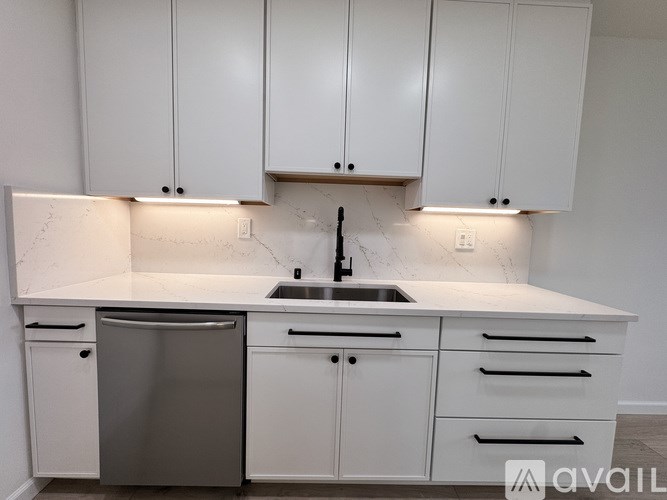 A kitchen with white cabinets and a stainless steel dishwasher.