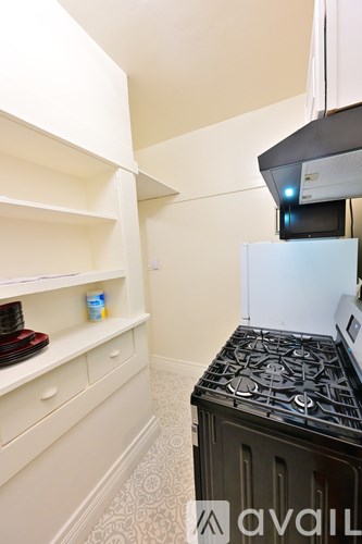 A kitchen with a black stove top oven and white cabinets.
