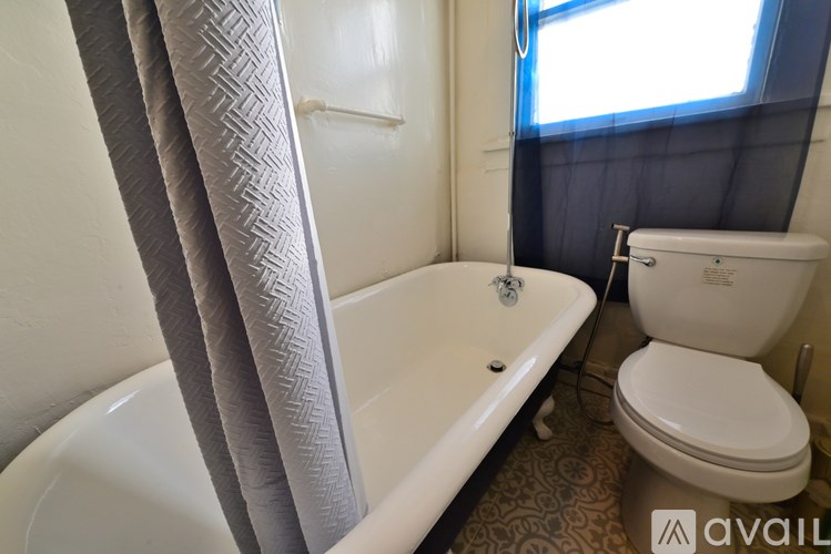 A bathroom with a white toilet and a white bathtub with a grey shower curtain.