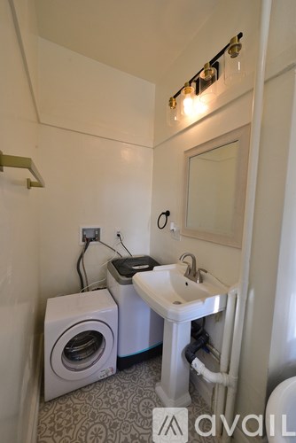 A small bathroom with a sink, mirror, and a washer and dryer.