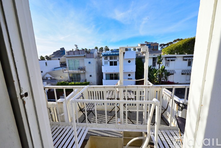 A balcony with white railings and chairs overlooks a residential area.