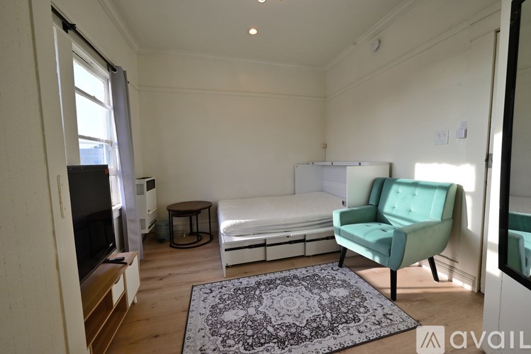 A living room with a white couch, a green armchair, a television, and a rug.