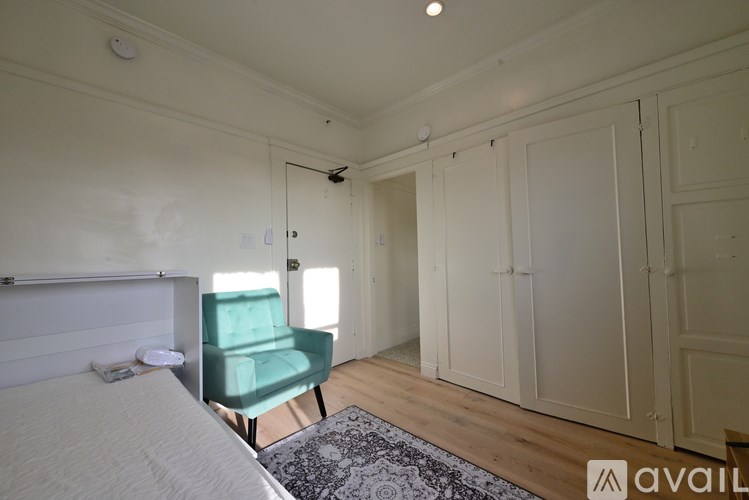 A bedroom with a bed, a green chair, and a wooden floor.