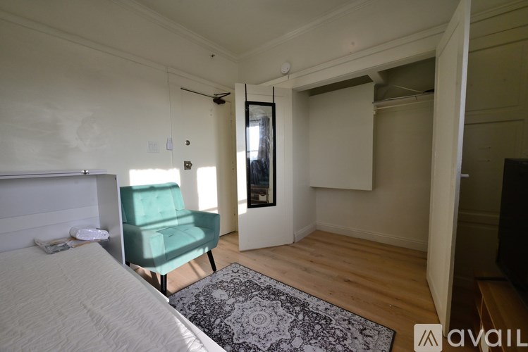 A bedroom with a bed, chair, and a rug.