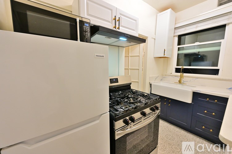 A kitchen with a white fridge, black stove, and white cabinets.