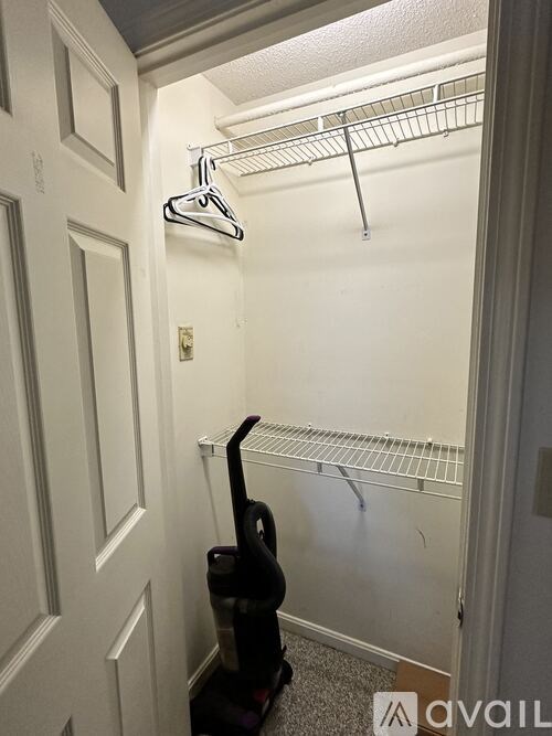 A small closet with a hanger and a vacuum cleaner.