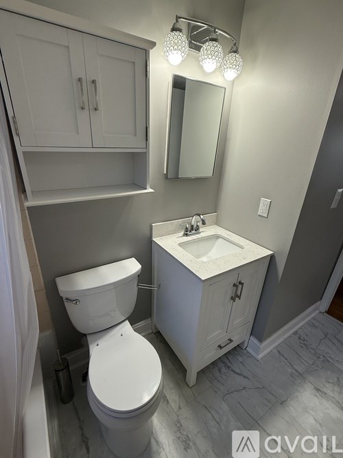 A white toilet sits under a mirror in a bathroom.