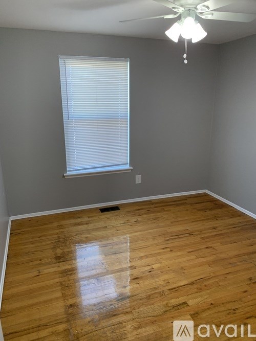 A room with wooden flooring and a window with blinds.