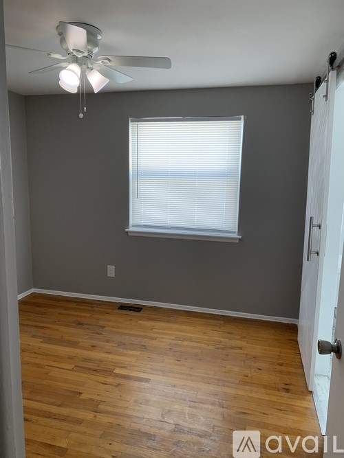 A room with a ceiling fan and a window with blinds.