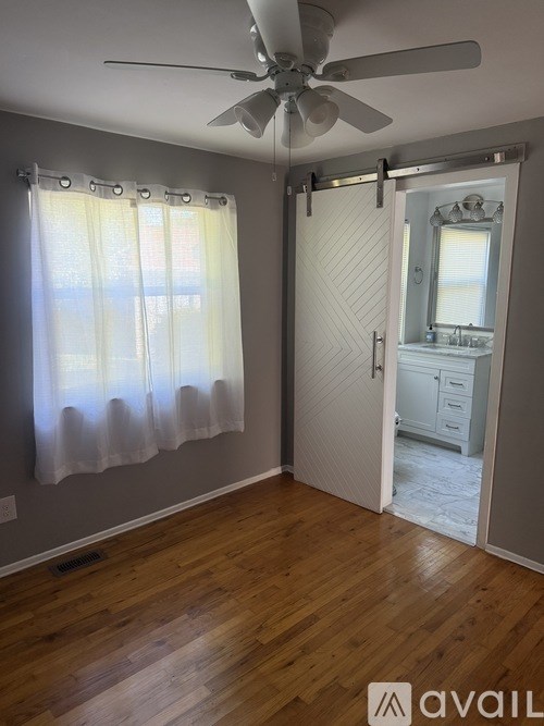 A room with a ceiling fan and a sliding door leading to another room.