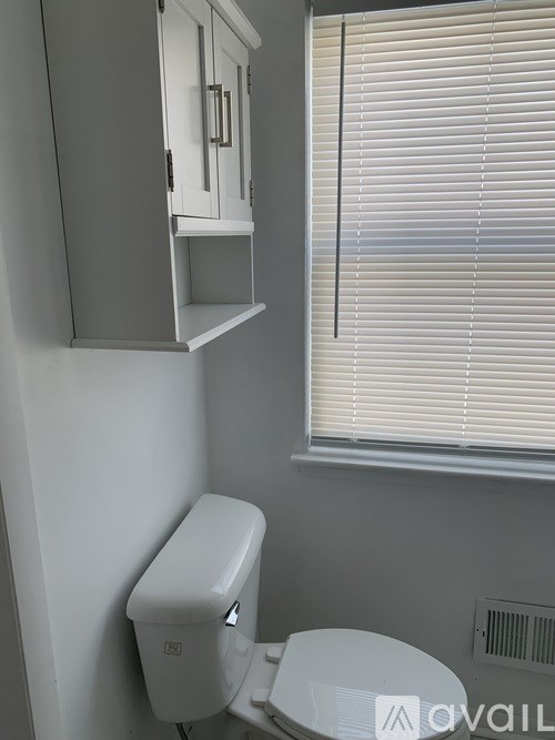 A white toilet with a white cabinet above it.