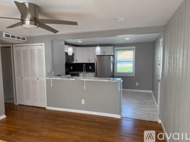 A kitchen with a refrigerator, cabinets, and a ceiling fan.