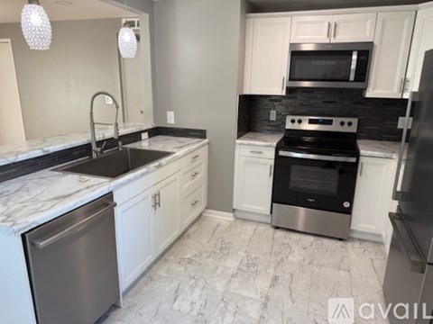 A modern kitchen with white cabinets and a marble countertop.