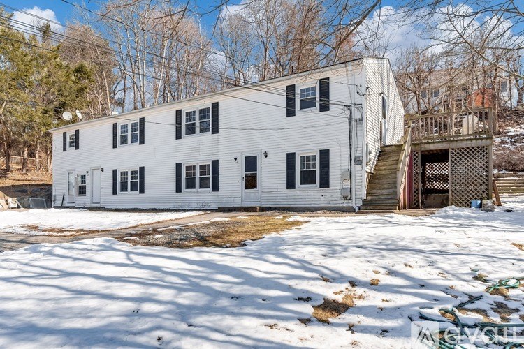 A white building with black shutters sits in a snowy field.