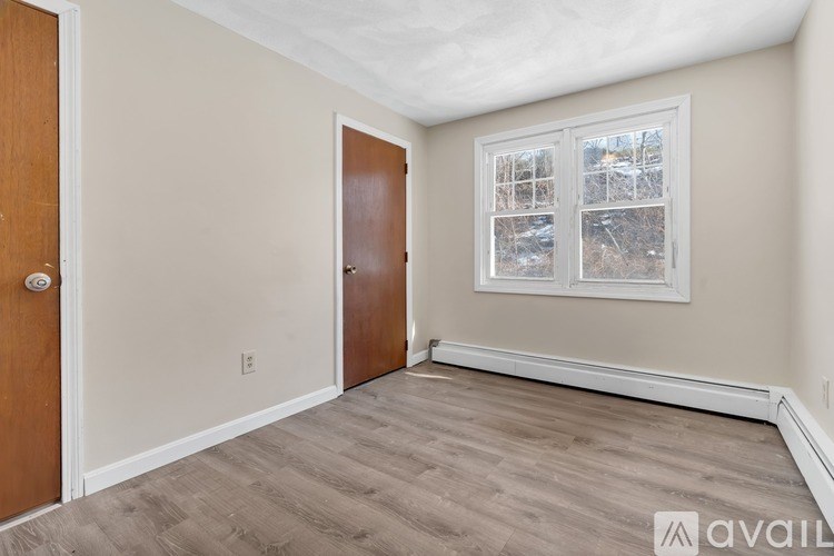 A room with a wooden door and a window with a view of a snowy landscape.