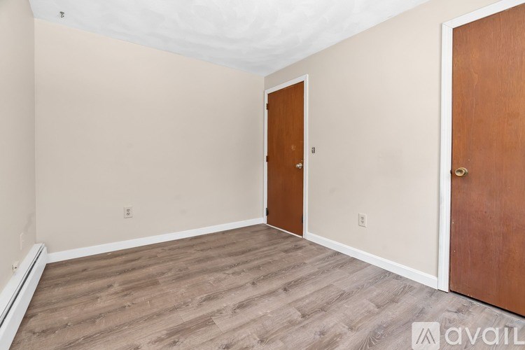 A room with a wooden floor and two doors.