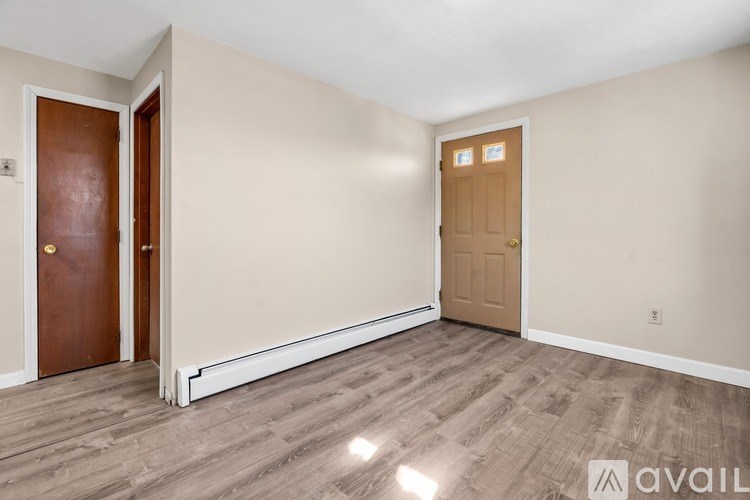 A room with a brown door and a white door with a wall and floor made of wood.