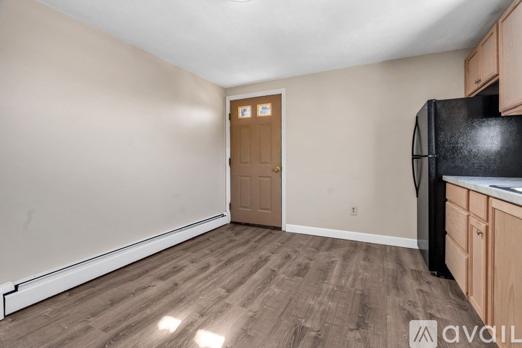 A kitchen with a black fridge and wooden floors.