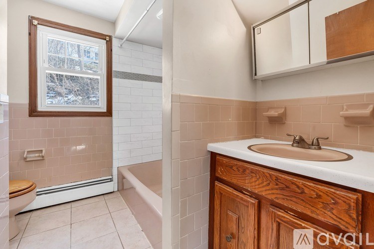 A bathroom with a toilet, sink, and a window.