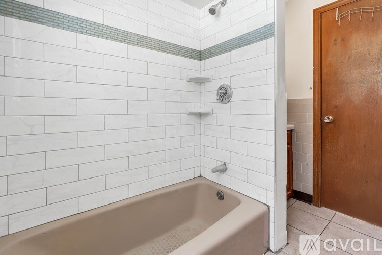 A bathroom with a white tiled shower and a beige bathtub.