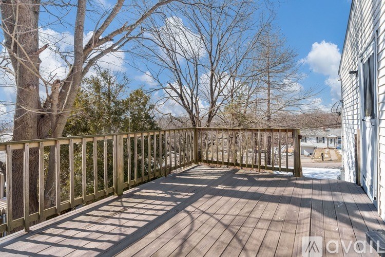 A wooden deck with a railing and bare trees in the background.