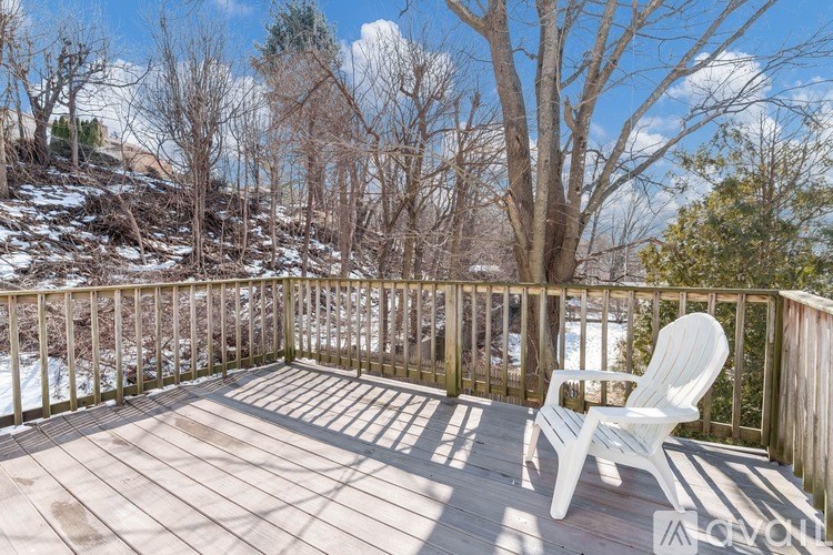 A white chair is on a wooden deck with trees in the background.