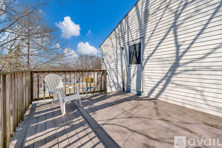 A white chair is on a wooden deck in front of a house.