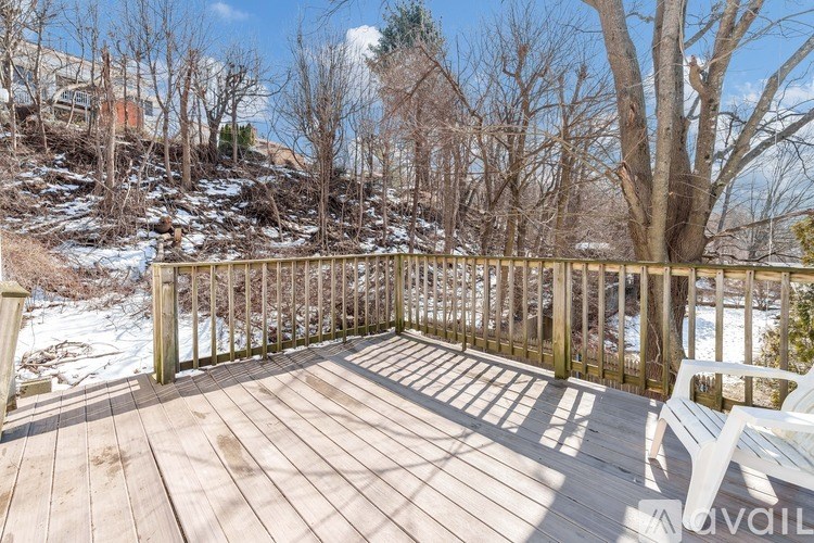 A wooden deck with a bench and snow on the ground.