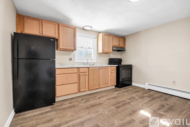 A kitchen with black fridge and wooden cabinets.