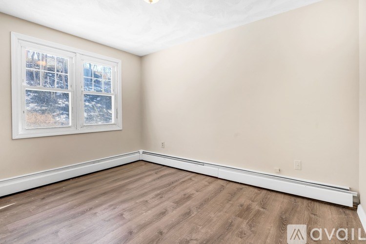 A room with a window and wooden flooring is available for rent.
