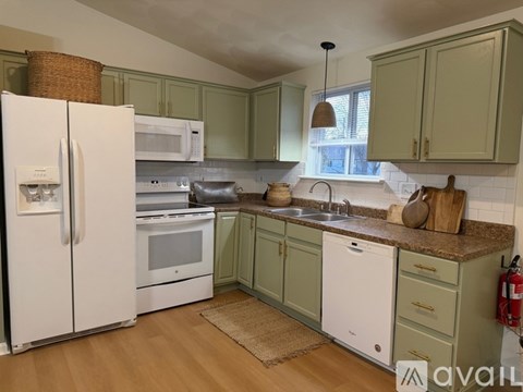 A kitchen with green cabinets and white appliances.