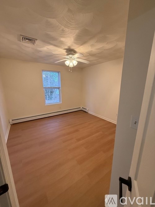 A room with wooden flooring and a ceiling fan.
