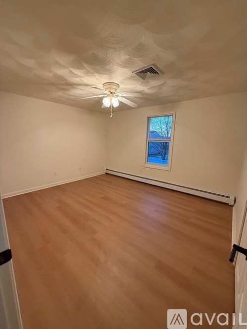 A room with wooden flooring and a ceiling fan with a light.