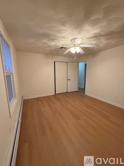 A room with a ceiling fan and wooden flooring.