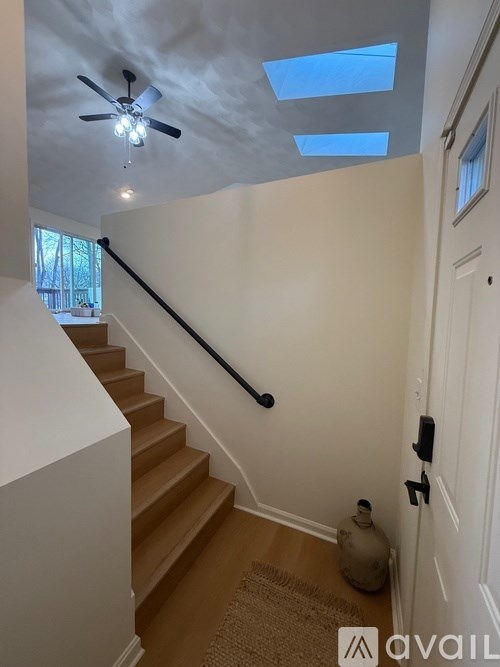 A hallway with a staircase and a ceiling fan.