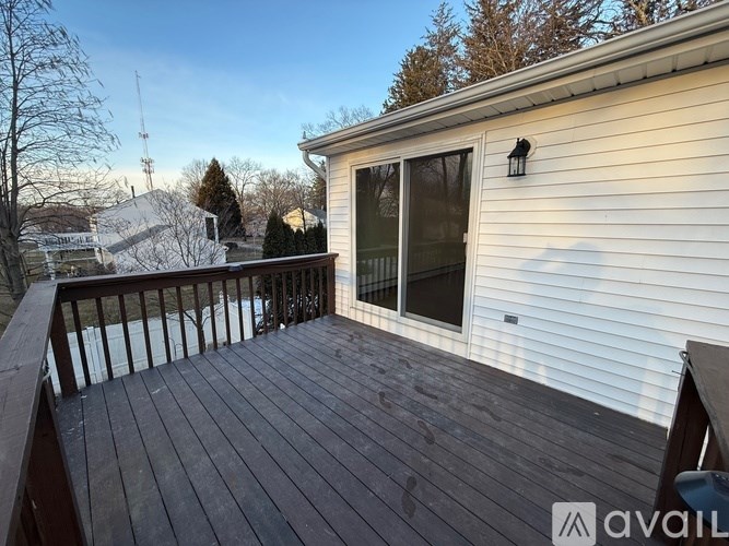 A wooden deck with a sliding glass door and a railing.