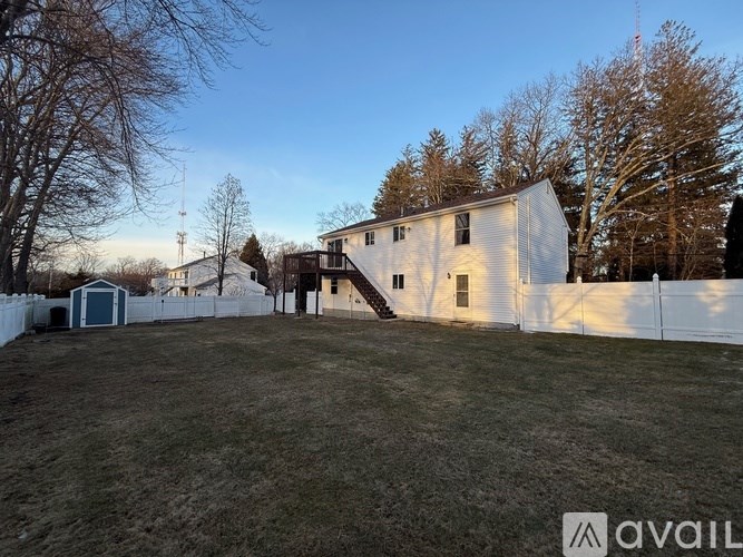 A white house with a fence and trees in the background.