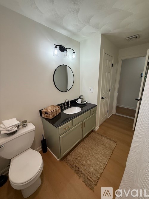A bathroom with a toilet, sink, mirror, and lights.