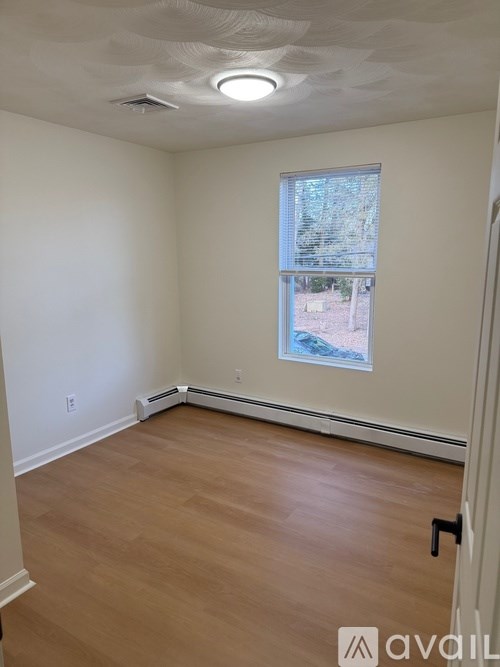 A room with a window and a wooden floor.