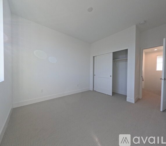 A white room with a carpeted floor and a doorway leading to another room.