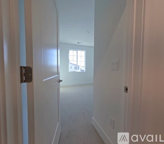 A hallway with a door on the left and a window in the distance.