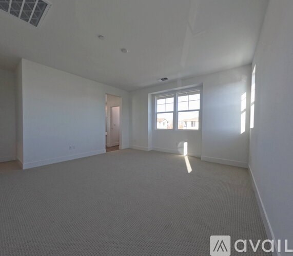 A spacious room with a carpeted floor and a window letting in natural light.