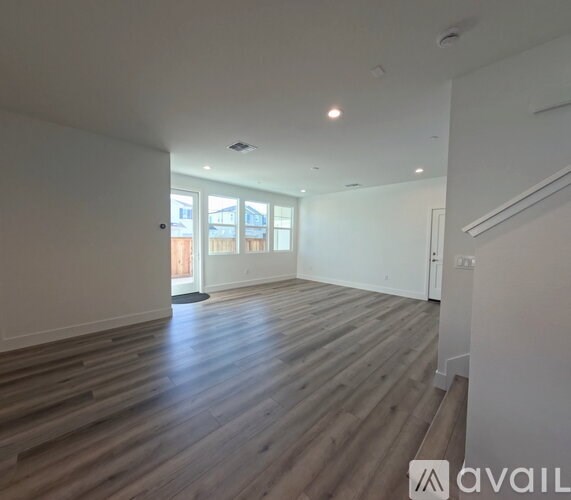 A spacious room with wooden flooring and a large window.