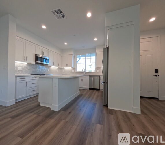 A kitchen with white cabinets and a wooden floor.