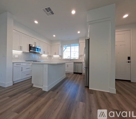 A kitchen with white cabinets and a wooden floor.