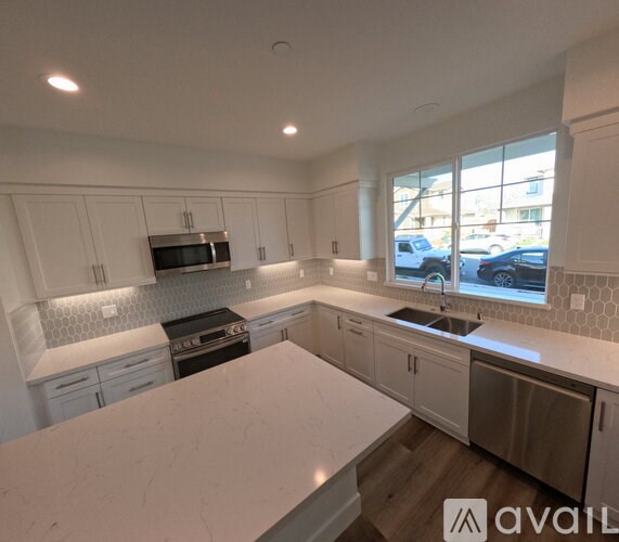 A kitchen with white cabinets and a marble countertop.