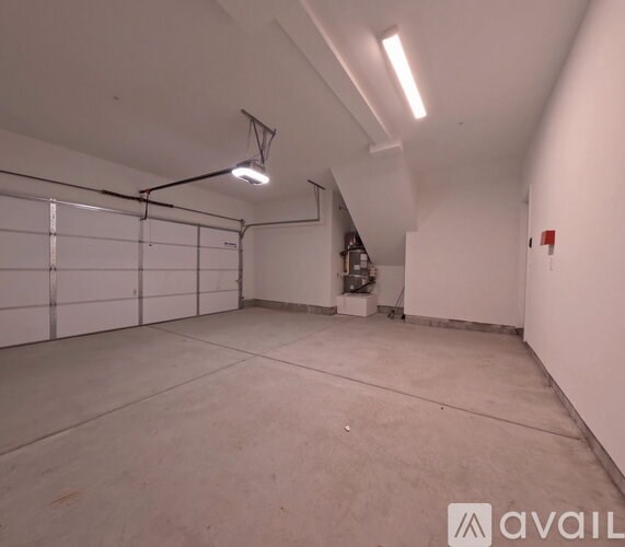 A spacious garage with a white wall and a hanging light fixture.