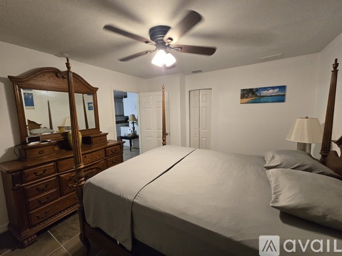 A kitchen with a black fridge, white cabinets, and a ceiling fan.